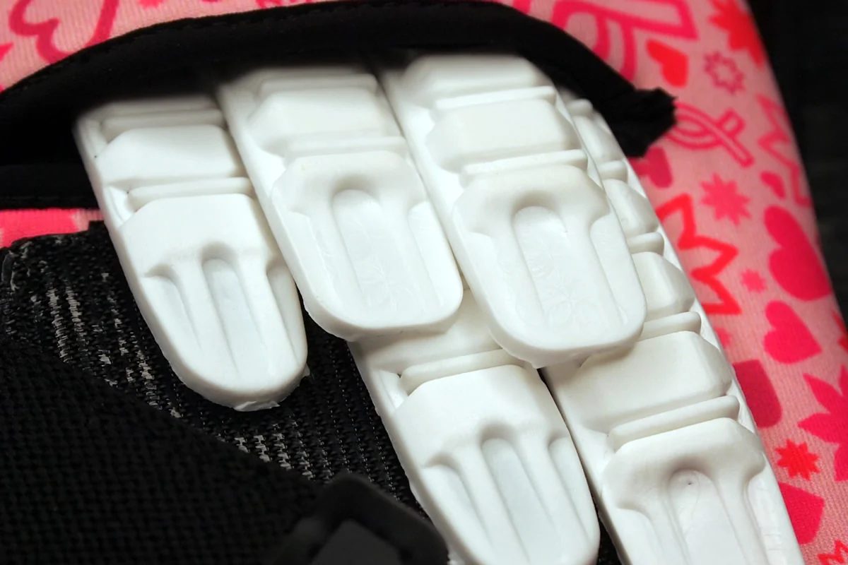 White finger spines sitting in the backhand of a pink goalkeeper glove, with the fabric cover pulled back to show them.