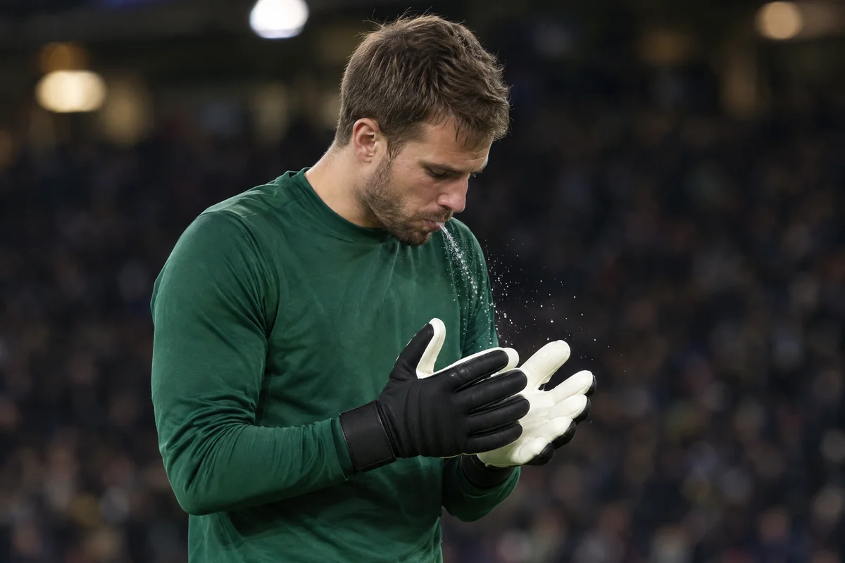 Goalkeeper spitting on the palms of his gloves before a match.